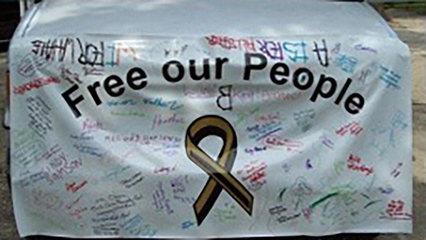 A banner with signatures on it that says “Free our People”